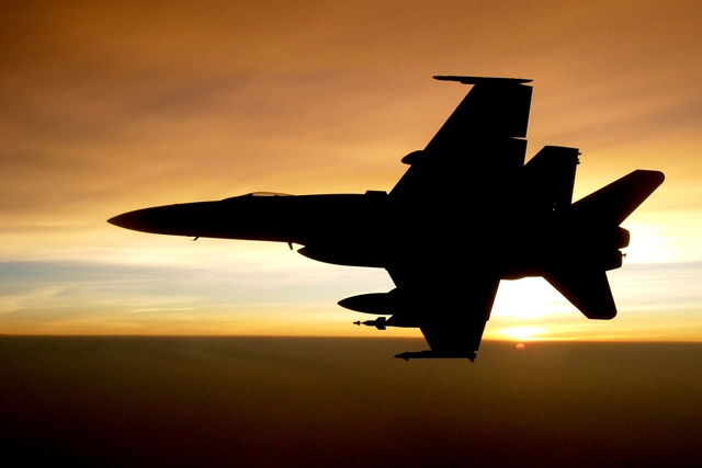 Fighter jet silhouette against sunset sky