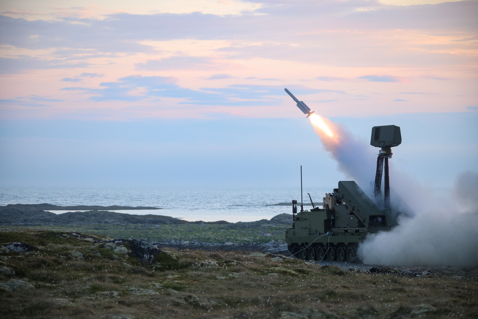 NASAMS air defense system launching a missile over coastal water and mountains